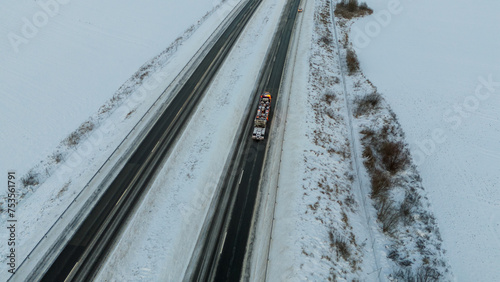 Drone photography of a truck towing a burned up lorry in a highway during winter morning
