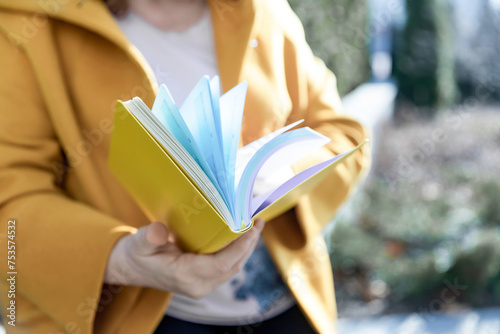 A woman in a yellow coat holds a flipping notebook photo