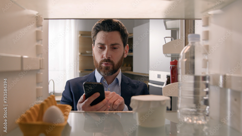 Point of view POV inside refrigerator Caucasian businessman employer man open fridge empty shelves with one egg and bottle of water order food with mobile delivery service buying products with phone Point of view POV inside refrigerator Caucasian businessman employer man open fridge empty shelves with one egg and bottle of water order food with mobile delivery service buying products with phone