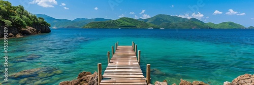 Scenic wooden walkway over turquoise ocean to overwater bungalows at tropical resort © Ilja