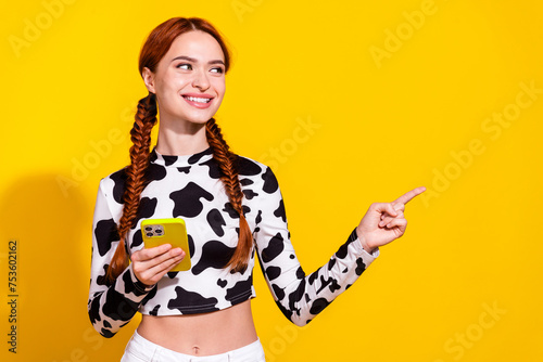 Photo of sweet cute woman wear cow skin top chatting apple iphone samsung gadget pointing empty space isolated yellow color background © deagreez