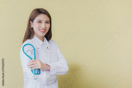 Young asian woman doctor standing with arms crossed confidently in hospital wearing medical uniform and stethoscope in the theme of health check while isolated white background.