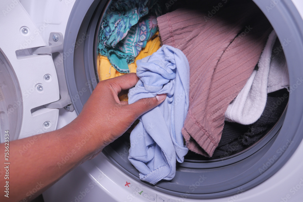  man putting shirt into washing machine.