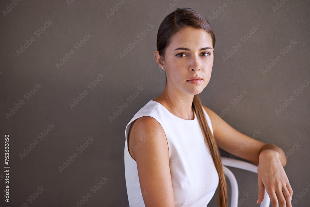 Woman, portrait and serious in chair in studio and relax by grey background for rest. French designer, glow and face in formal fashion or elegant and creative career with confidence in mock up Woman, portrait and serious in chair in studio and relax by grey background for rest. French designer, glow and face in formal fashion or elegant and creative career with confidence in mock up