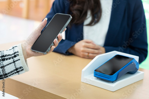 A woman using her mobile to made a payment wireless with EDC machine or credit card terminal. Mobile payment concept with virtual credit card. Shopping, retail and modern digital bank concept. photo