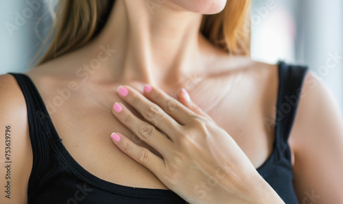 A woman with a pink manicured hand is wearing a black tank top. Concept of confidence and self-care  as the woman takes the time to paint her nails and wear a stylish outfit