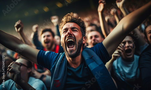 Exhilarated crowd of football/soccer fans cheering passionately in a stadium, expressing intense emotion and support during a thrilling football match photo