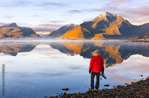 A photographer observes mountains and rorbuer in a Fjord during sunset, Leknes, Vestvagoy, Nordland, Lofoten Islands, Norway, Scandinavia photo