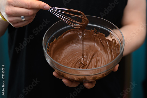 Miska z płynną błyszcząca polewą czekoladową z bliska w dłoniach 