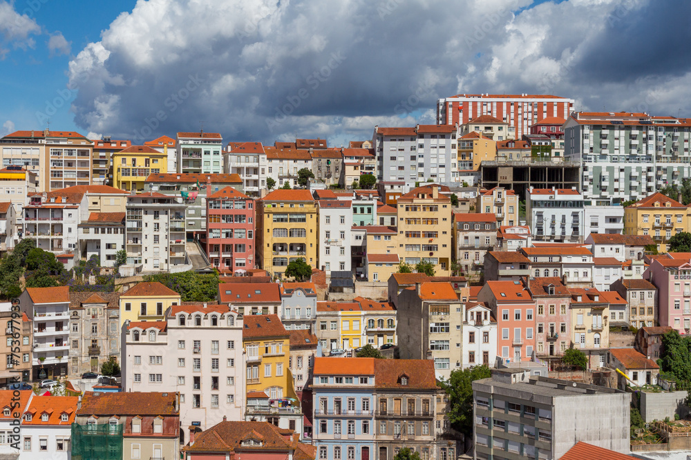 Cityscape of colorful traditional houses in Coimbra historic center with blue sky and heavy clouds, Portugal