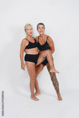Wallpaper Mural adult daughter carrying her mother on one leg smiling happy having fun together, white background Torontodigital.ca