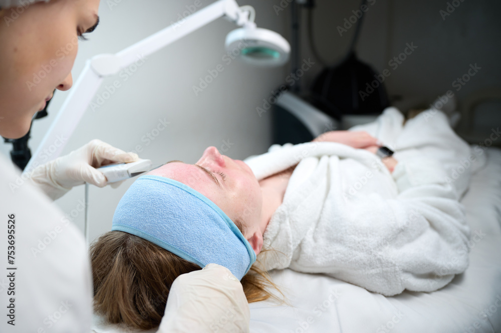 Close up of ultrasound skin cleaning and facial peeling procedure in beauty clinic. Macro shot of woman under procedure of ultrasonic facial. Deep pore cleansing treatment