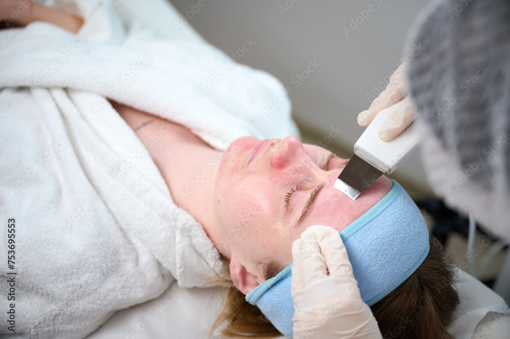 Close up of ultrasound skin cleaning and facial peeling procedure in beauty clinic. Macro shot of woman under procedure of ultrasonic facial. Deep pore cleansing treatment Close up of ultrasound skin cleaning and facial peeling procedure in beauty clinic. Macro shot of woman under procedure of ultrasonic facial. Deep pore cleansing treatment