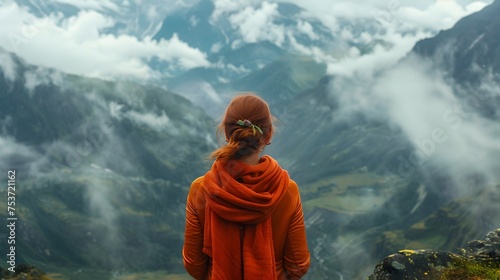 Woman in Orange Coat Standing on Mountain Peak in Gauzy Atmospheric Landscape