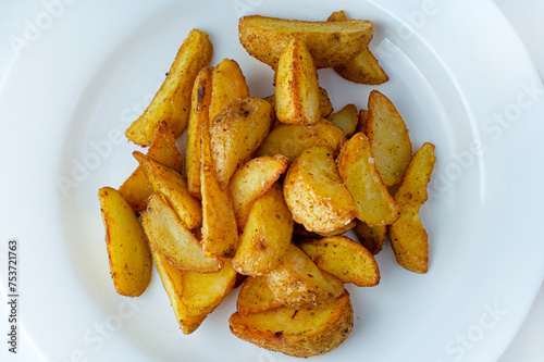 Baked potatoes on a white plate. Country-style potatoes.