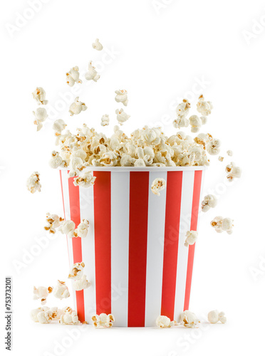 Popcorn falling from red and white striped container, isolated on white background.