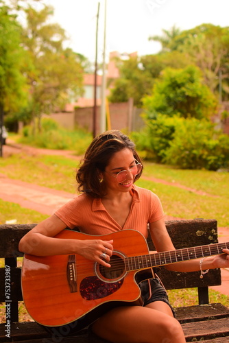 Mujer caucásica de nacionalidad argentina joven y hermosa tocando la guitarra en un paisaje