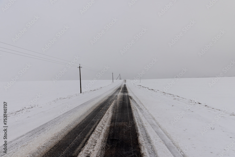 a snow-covered paved road in the winter season in a snowfall