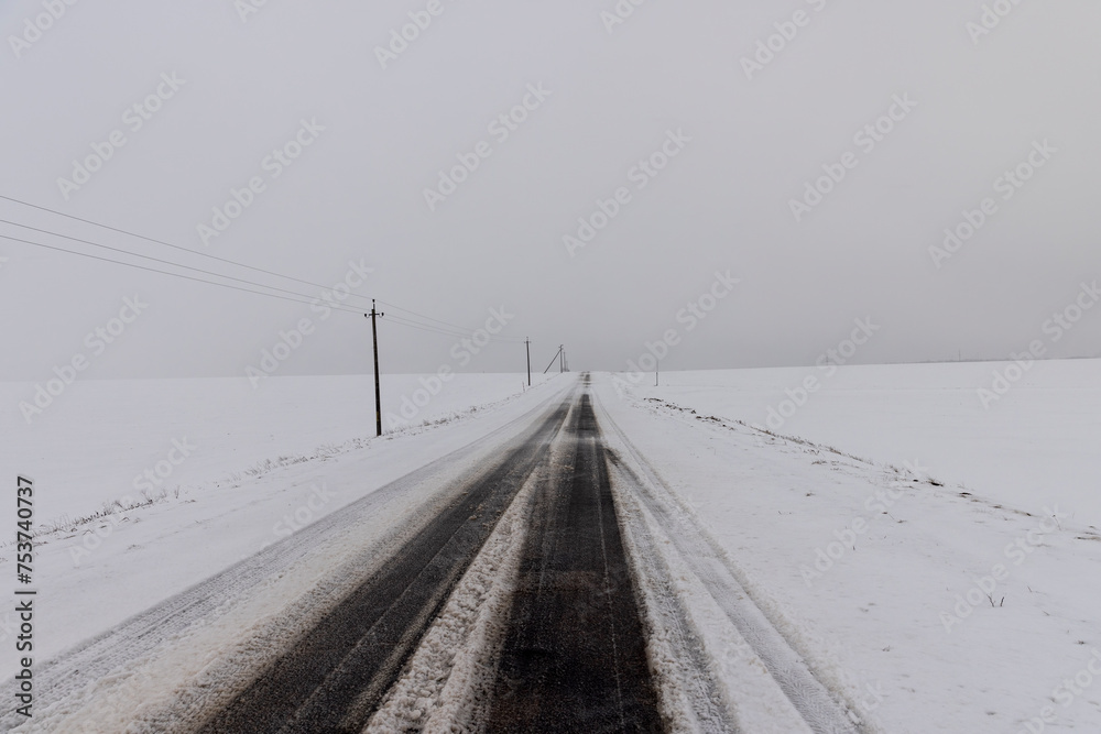 a snow-covered paved road in the winter season in a snowfall a snow-covered paved road in the winter season in a snowfall