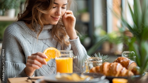 woman has breakfast at home with orange juice and croissant, vertical photo 