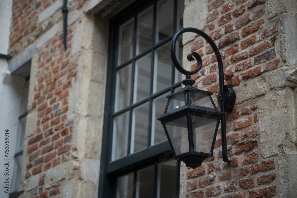 closeup of metallic old street lamp on brick wall facade in the street