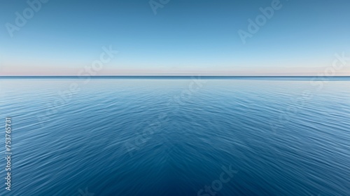 a large body of water with a blue sky in the background and a few clouds in the sky above it. © Ilona