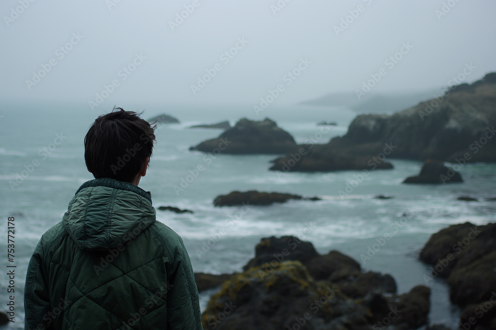 Solitary person gazing at the rugged coastal landscape on an overcast day Solitary person gazing at the rugged coastal landscape on an overcast day