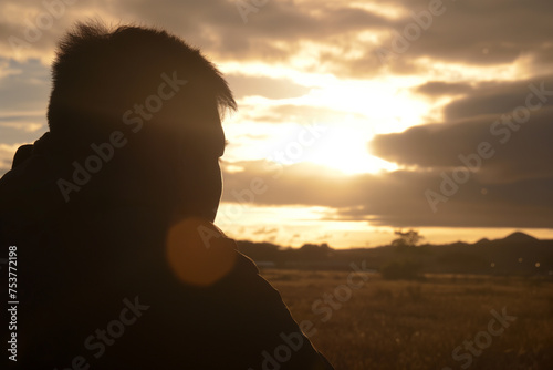 Silhouette of a man against a golden sunset sky in the countryside