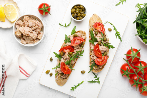 Tuna caper toasts with arugula, tomatoes and whole rye bread, top view