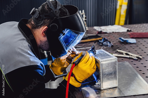 Man performs welding work at his workplace. Welding an aluminum tank with an argon welding machine.
