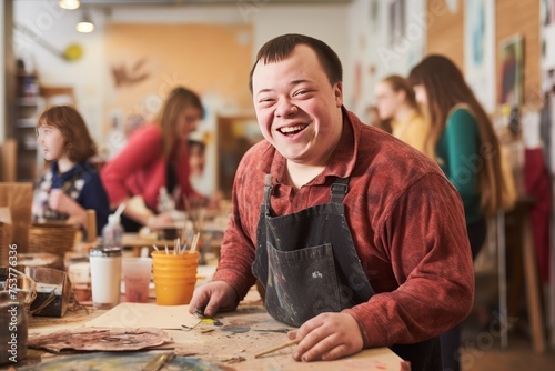 Young smiling man with Down syndrome on art workshop with a group of students high resolution --ar 3:2 Job ID: e562660a-8c61-4cbb-bad6-aef6c8ec51cf