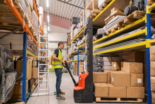 Person Using Manual Forklift At Warehouse photo