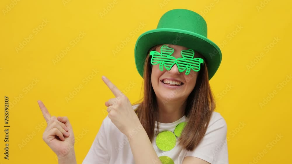 Smiling happy cheerful woman wearing leprechaun party green hat isolated over yellow background pointing away at copy space for promotional text expressing happiness Smiling happy cheerful woman wearing leprechaun party green hat isolated over yellow background pointing away at copy space for promotional text expressing happiness