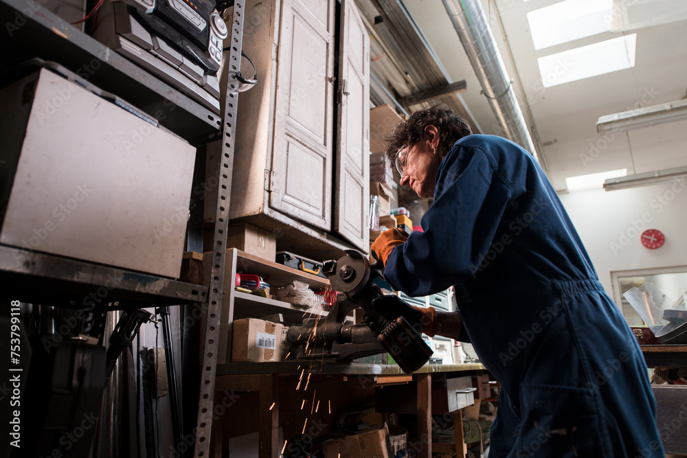 Focused woman working with angle grinder at factory Focused woman working with angle grinder at factory