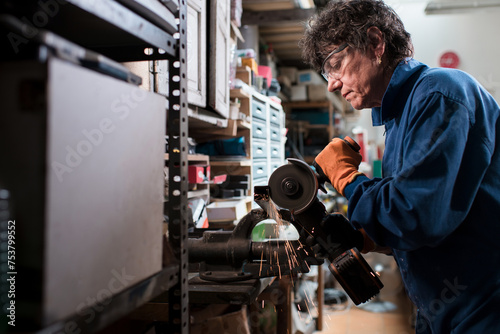 Mature woman working with angle grinder at workshop photo