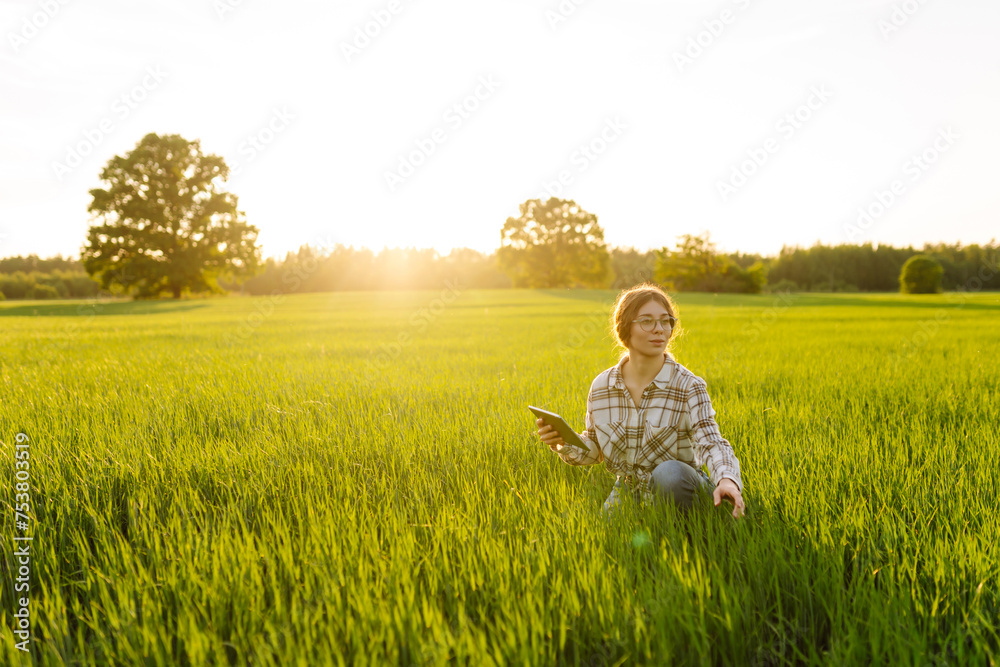 A woman farmer with a modern tablet in green field. Concept for farm development, horticulture. A woman farmer with a modern tablet in green field. Concept for farm development, horticulture.