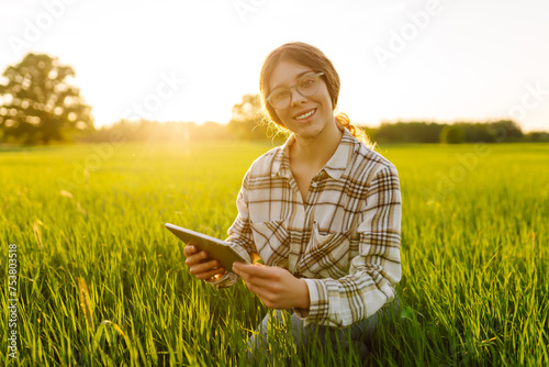 A woman farmer with a modern tablet in green field. Concept for farm development, horticulture.