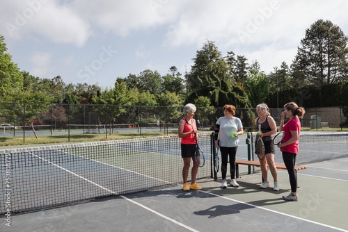Four women hanging out and chatting at the tennis court in the s
