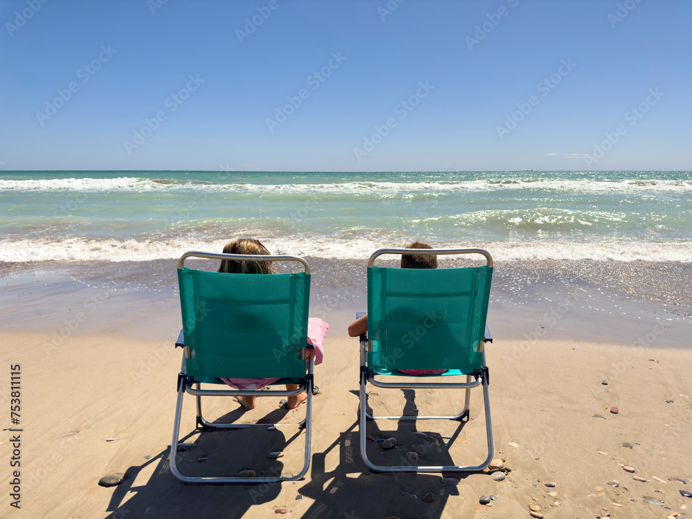 Kids relaxing on deckchairs near wavy ocean. UGC Kids relaxing on deckchairs near wavy ocean. UGC