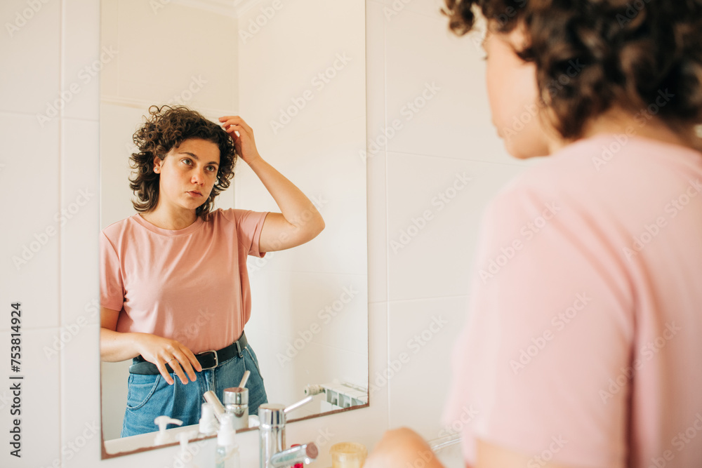 Woman looking at her reflection in the mirror Woman looking at her reflection in the mirror