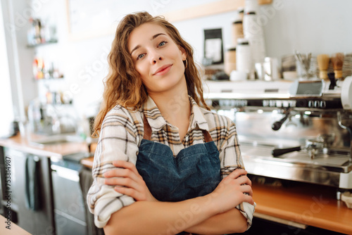 Young woman cafe owner in an apron looks at the camera and smiles. Business concept. Food and drink concept.