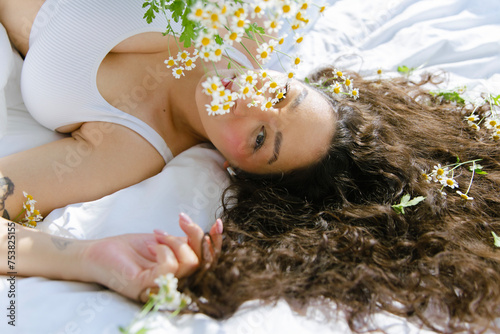 Beautiful young woman with curly hair, chamomile in hair