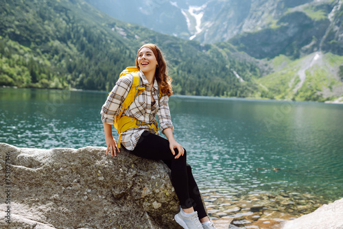 Active woman enjoys the beautiful scenery of the majestic mountains and lake. Travel, adventure. Concept of an active lifestyle.