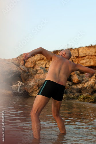 Man in black short playing in the sea doing ricochet with a stone