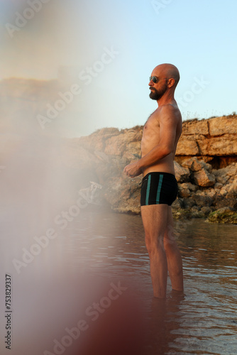 Man in black short playing in the sea doing ricochet with a stone