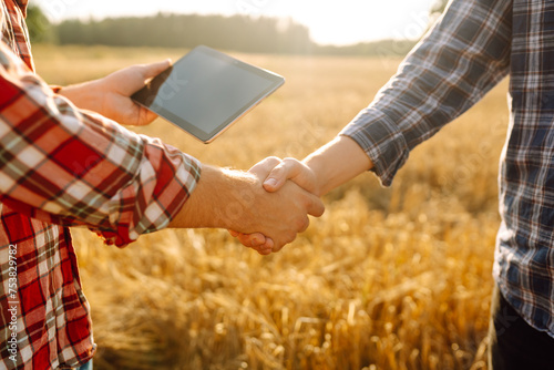 Handshake. Two farmer standing and shaking hands in a wheat field. Agricultural business. photo