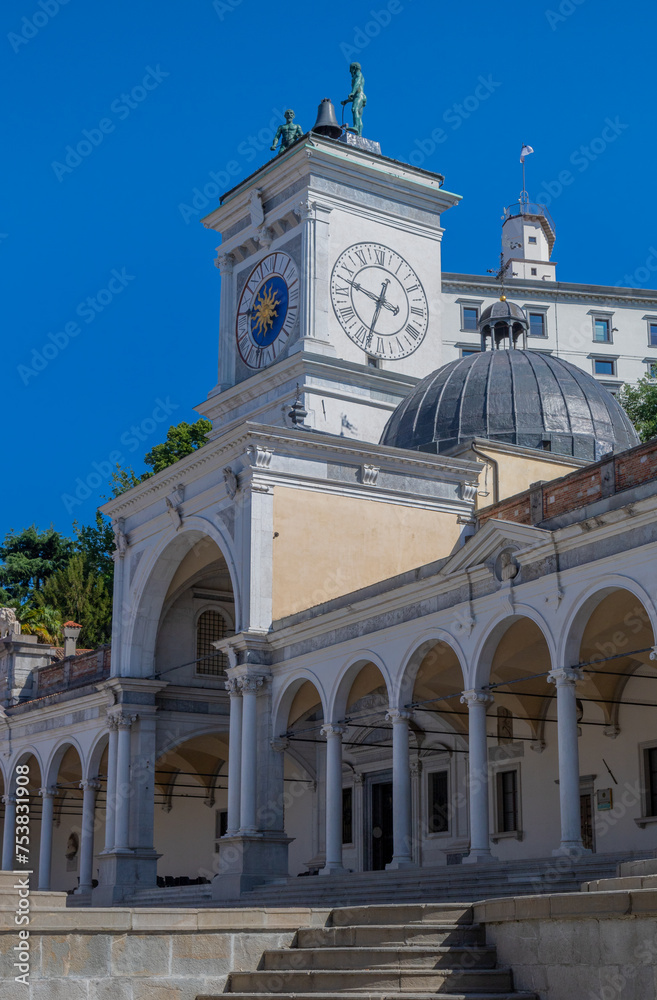Beautiful white building  with arches, clock tower, Torre dell'Orologio, in Loggia di San Giovanni located in Piazza della Libertà with a sculpture hitting a bell above the tower in Udine.
