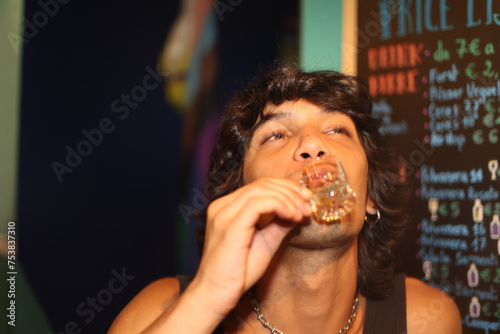 Young alternative man doing shots at bar on the street at night photo