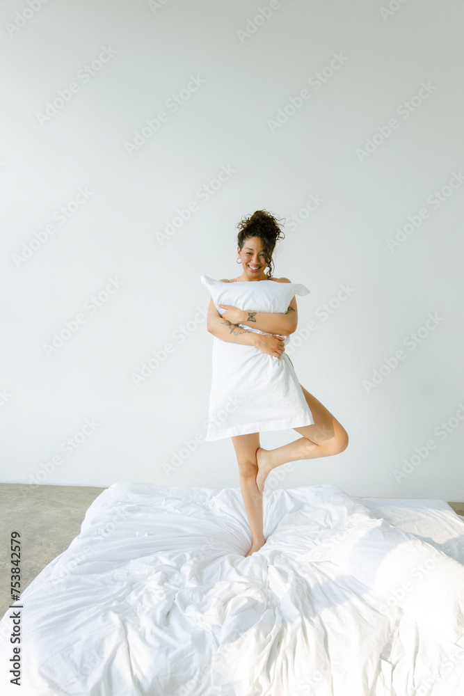 Woman Holding Pillows and standing on a white bed
Woman Holding Pillows and standing on a white bed