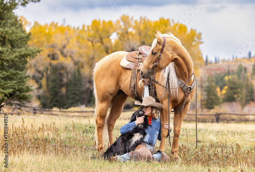 Fotografija Colorado Cowgirl with a palomino horse and her herding dog in the mountains with